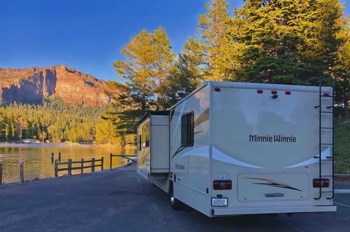 Winnebago Minnie Winnie RV rental by a serene lake, framed by majestic mountains and golden trees.. Winnebago Minnie Winnie 2019