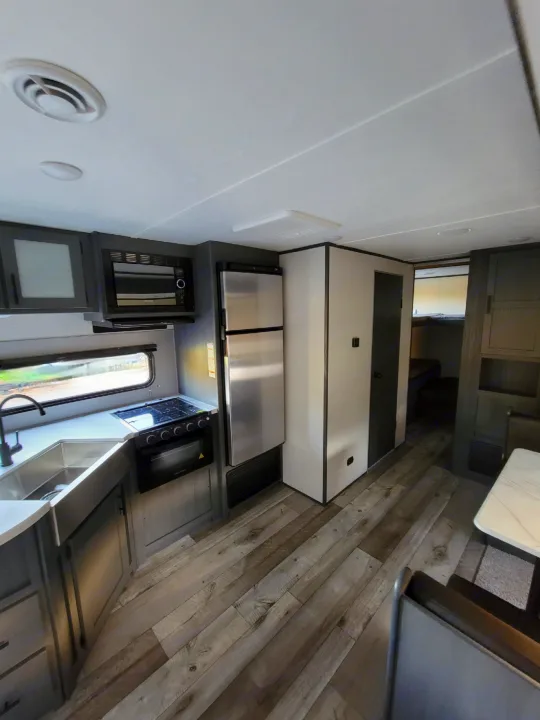 Spacious RV rental interior featuring a complete kitchen (sink, stove, fridge), dining, and bedroom access.. Dutchman Aspen Trail 2022