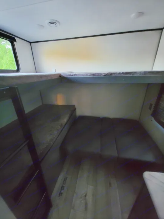 RV rental interior: a compact living space with dark dining cushions, a bed/bunk, and a window.. Dutchman Aspen Trail 2022