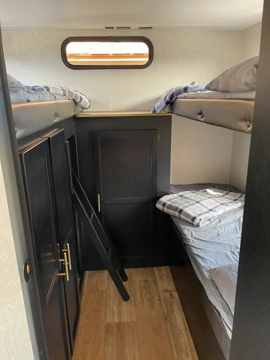 RV rental interior: A compact bunk room with two beds, a ladder, and dark storage cabinetry.. Forest River Cherokee Grey Wolf 2022