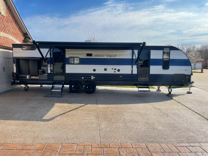 Modern Grey Wolf RV travel trailer, featuring an outdoor kitchen, parked at home. Perfect for an exciting rv rental!. Forest River Cherokee Grey Wolf 2022