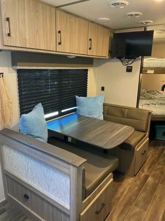 Modern RV rental interior: dinette with storage, TV, and cozy bunk beds. Perfect for family adventures.. Keystone RV Passport SL 2021