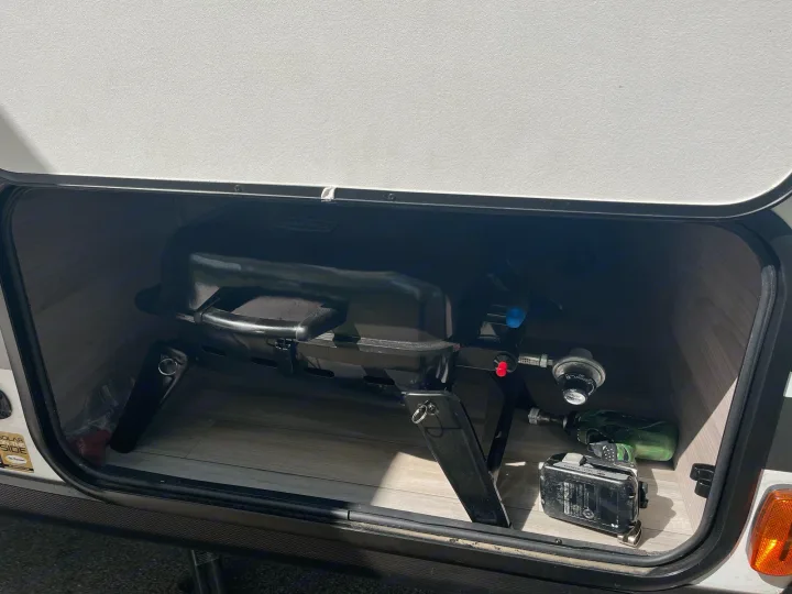 RV rental: The lower storage compartment reveals a portable propane grill, power tools, and a battery.. Coachmen 2549 BHX 2021