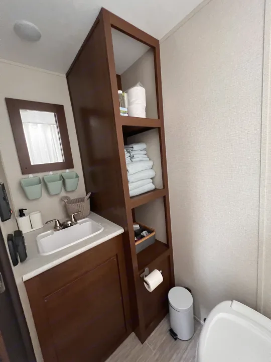 This RV rental bathroom offers a compact vanity with sink & mirror, practical shelving for essentials, and a toilet.. PTX Forest River PDX170 2019