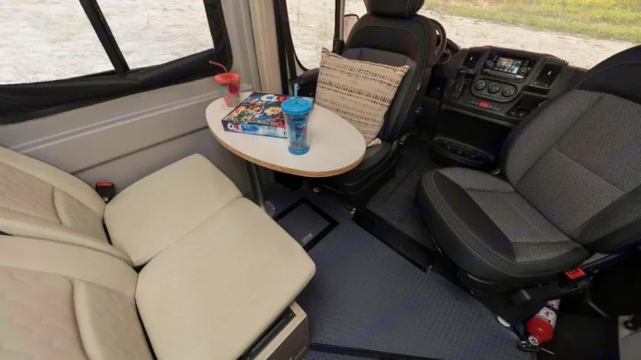 Inside an RV rental: versatile seating, a dining table with games & drinks, and a full front cabin. Ready for your trip!. Winnebago Solis 2021