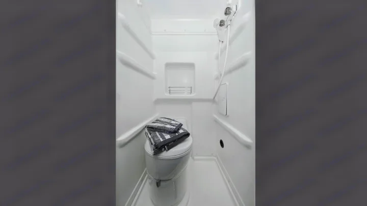 Inside an RV rental: compact white bathroom with toilet, shower & shelf.. Winnebago Solis 2021