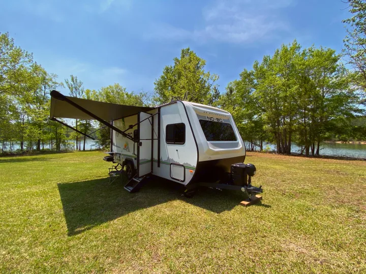 This modern RV rental is perfectly set up for a serene lakeside camping trip on lush green grass under a blue sky.. Forest River Other 2022