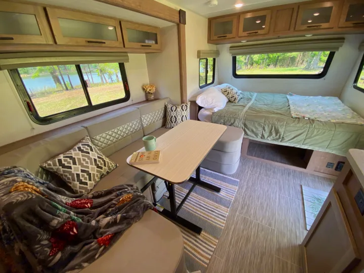 Spacious RV rental interior: A cozy lounge/dining area, a comfortable bed, and scenic lake views through the windows.. Forest River Other 2022