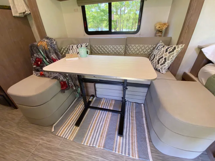 Cozy RV rental dinette with U-shaped seating, table, and scenic window view, perfect for travel.. Forest River Other 2022