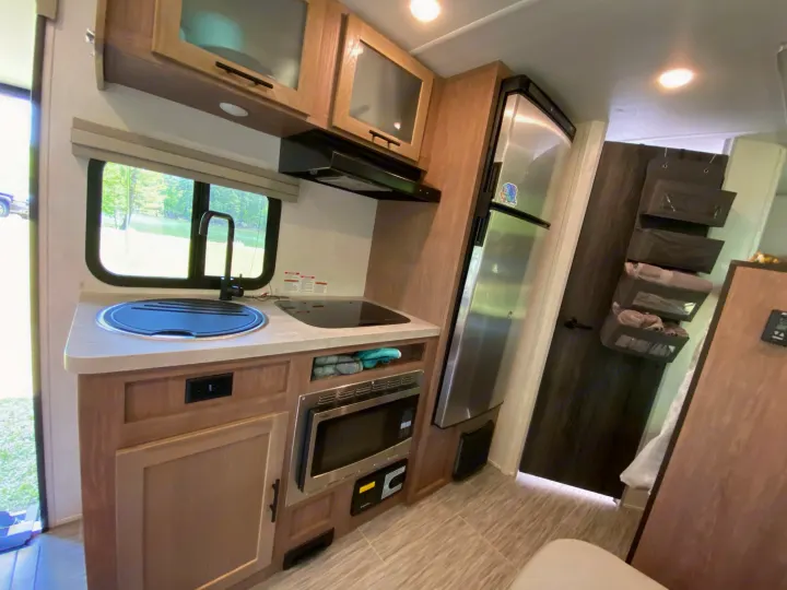 Step into this bright RV rental kitchen, showing a modern sink, cooktop, microwave, and refrigerator, optimized for travel comfort.. Forest River Other 2022