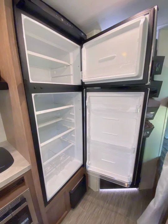 An empty, clean two-door RV refrigerator with top freezer, ready for your rv rental adventure and stocking.. Forest River Other 2022