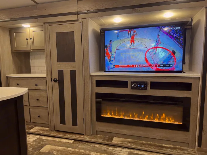 Modern RV rental living space with a TV, electric fireplace, and ample storage, ideal for comfortable travel.. Keystone Outback 2020