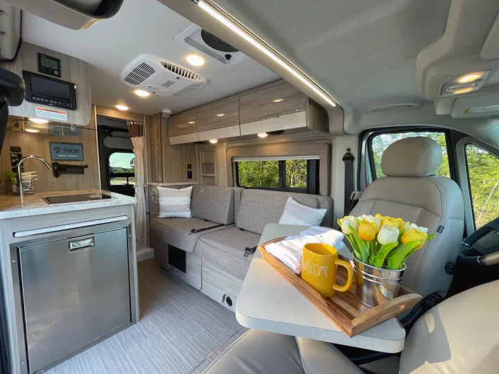 Modern RV rental interior, bright & comfortable with a kitchenette, sofa, and welcome tray, ready for travel.. Thor Scope 18M 2022