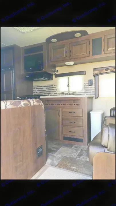 RV rental interior features a functional kitchen with microwave, sink, dark wood cabinetry, dinette, and comfortable living area.. Jayco Coyote 2014