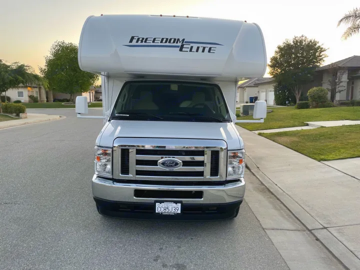 White Ford Freedom Elite Class C RV rental parked on a quiet residential street, front view showing license plate.. THOR MOTOR COACH FREEDOM ELITE 22fef 2022