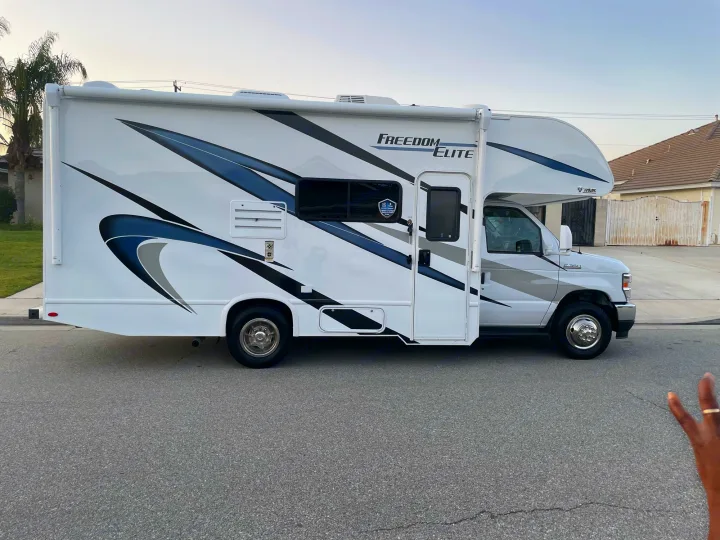 White Freedom Elite Class C RV rental with blue/grey graphics, parked on a residential street.. THOR MOTOR COACH FREEDOM ELITE 22fef 2022