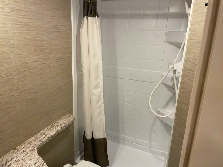 Compact RV rental bathroom featuring a white shower stall with curtain, and a granite-style counter.. THOR MOTOR COACH FREEDOM ELITE 22fef 2022