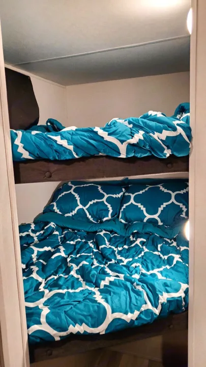 Cozy RV rental bunk beds featuring vibrant teal patterned bedding, perfect for comfortable sleeping arrangements in a compact space.. Forest River PRIME TIME 2022