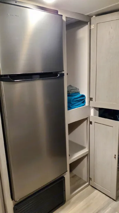 RV rental interior: Stainless steel refrigerator, open cabinets with towels, and shelving for organized storage.. Forest River PRIME TIME 2022