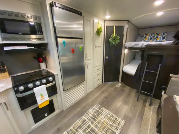 RV rental interior featuring a full kitchen with microwave, stove, and fridge, plus cozy bunk beds.. Jayco Jay Flight 2021