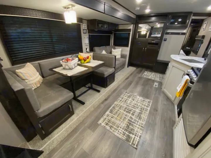 Spacious RV rental interior featuring a modern dining booth, full kitchen, and wood-look flooring. Perfect for your next adventure.. Jayco Jay Flight 2021