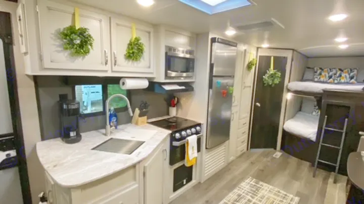 Inside a spacious rv rental, featuring a full kitchen with a microwave & fridge, plus comfy bunk beds.. Jayco Jay Flight 2021