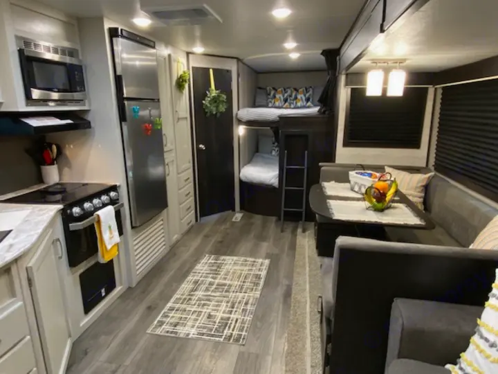 Modern RV rental interior: kitchen, cozy dining area, and bunk beds. Ideal for family adventures.. Jayco Jay Flight 2021
