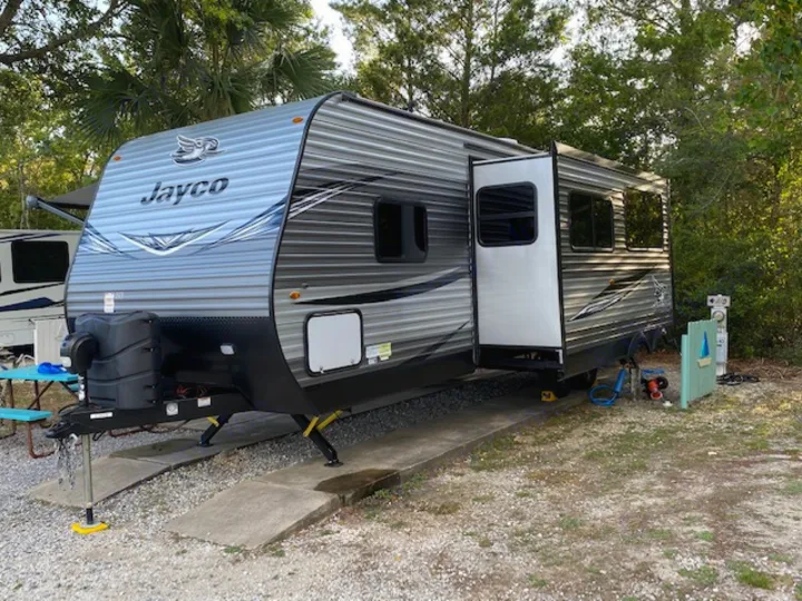 This modern Jayco RV rental, with its slide-out extended, is perfectly set up at a scenic gravel campsite.. Jayco Jay Flight 2021