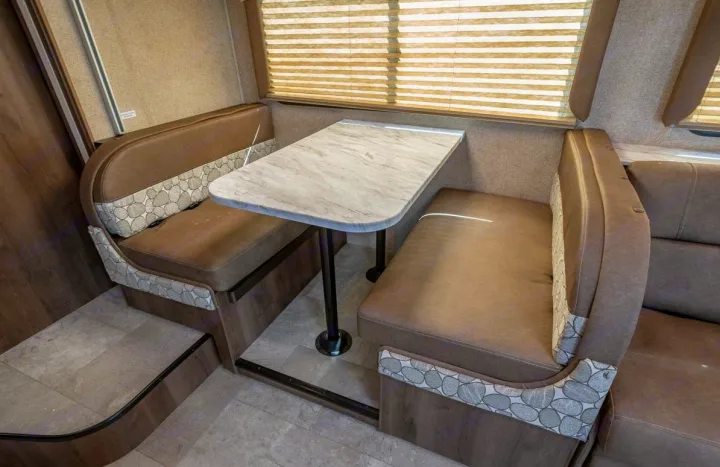 Cozy RV rental dinette with two comfortable bench seats and a versatile table, perfect for meals and relaxation.. Coachmen Freelander 28BH 2018