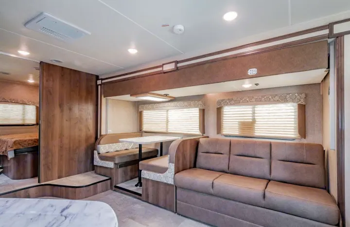 Spacious RV rental interior with living area, dinette, and visible bedroom, featuring comfy seating and modern decor.. Coachmen Freelander 28BH 2018