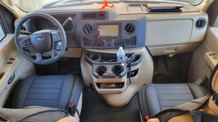 RV rental interior: Ford E-Series cockpit view with dashboard, steering wheel, cup holders, and padded front seats.. Ford Freedom Elite 2022