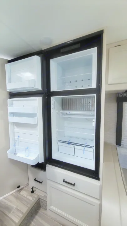 Dometic refrigerator & freezer in an RV rental, doors open revealing empty white interior shelves.. Ford Freedom Elite 2022