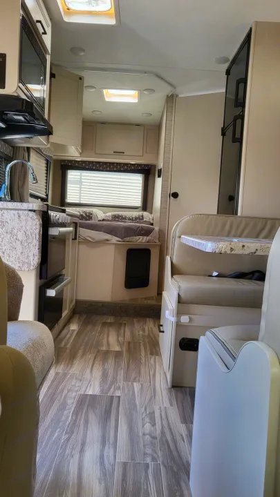 This RV rental offers a cozy interior with a full kitchenette, comfortable bed, and dinette, ideal for travel adventures.. Ford Freedom Elite 2022