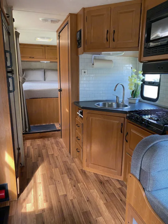 Bright and modern RV rental interior with a well-equipped kitchen, cozy bedroom, and sleek wood flooring. Ready for adventure!. Thor Majestic 2013
