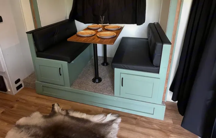 Cozy RV rental dinette featuring mint green benches with black cushions, a wood table, and storage cabinets.. Forest River Coachmen Apex Nano Off-Grid 2022
