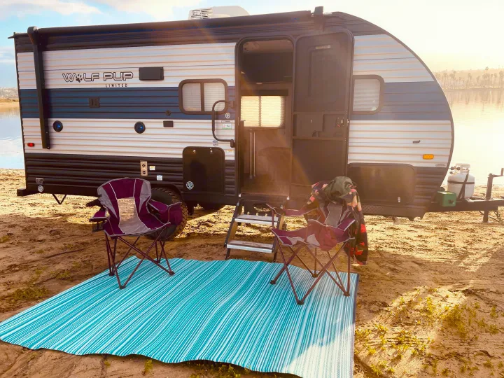 Enjoy the outdoors! This Wolf Pup rv rental offers a perfect waterfront setup with camping chairs and a cozy mat.. Forest River Cherokee Wolf Pup 2021