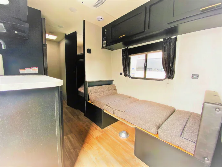 This rv rental interior features a convertible sofa bed, overhead cabinets, and bunk beds, offering a cozy and functional space.. Forest River Cherokee Wolf Pup 2022