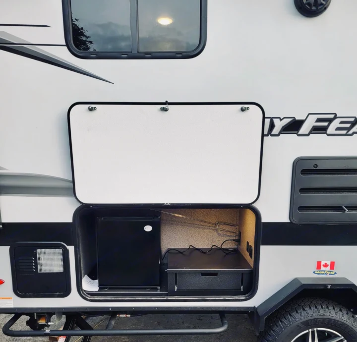RV rental with exterior compartment open, showing a mini-fridge and outdoor kitchen setup.. jayco Jay feather 199mbs 2022
