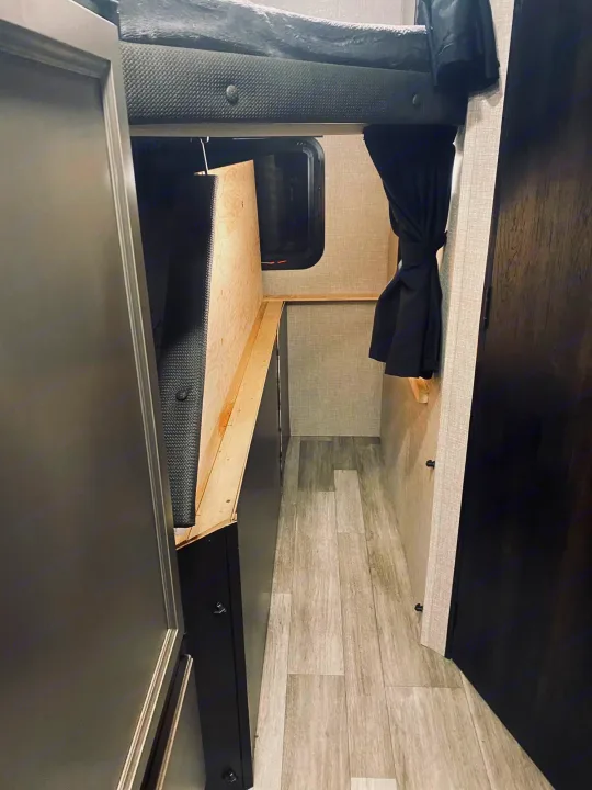 Cozy RV rental interior: a bunk bed above a narrow hallway with wood flooring, a window, and dark cabinetry.. jayco Jay feather 199mbs 2022