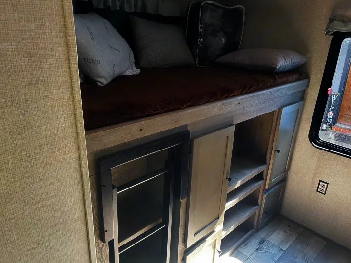 Cozy RV rental bunk bed setup with ample storage and a window, perfect for family travel adventures.. Keystone RV Outback 2021