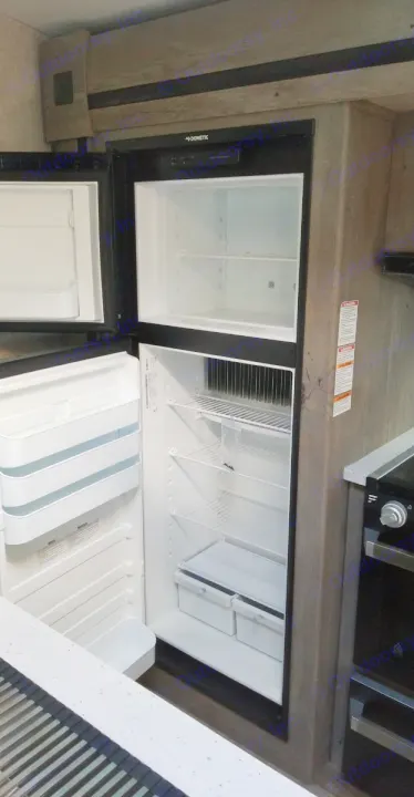 Inside an RV rental: view of the open Dometic refrigerator, showcasing spacious, clean freezer & fridge compartments.. Keystone RV Outback 2021