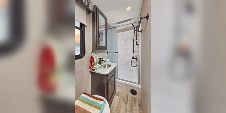 This RV rental bathroom features a compact shower, sink, and toilet, offering a comfortable space with a view.. Jayco ALANTE 27a 2022