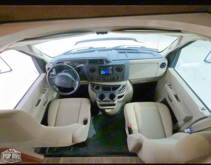 RV rental cockpit: Overhead view of tan driver/passenger seats, steering wheel, and dashboard with central display.. Itasca Spirit 2014