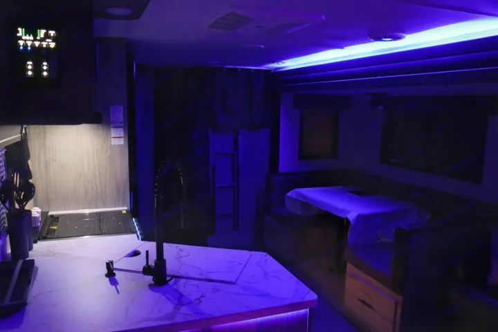 Modern RV rental interior with ambient blue lighting. Features a full kitchen, dining booth, and comfortable amenities for your trip.. Forest River Cherokee Alpha Wolf 2022
