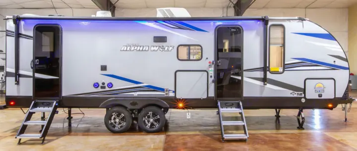 This modern grey Cherokee Alpha Wolf travel trailer RV with blue LED lights and graphic accents is ideal for rv rental.. Forest River Cherokee Alpha Wolf 2022