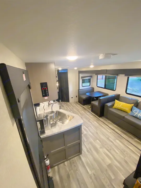 This RV rental's spacious interior features a modern kitchen, sofa living area, and dining booth with light wood floors.. Starcraft Super Lite 2022