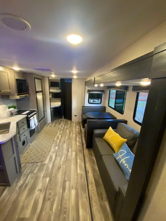 Spacious RV rental interior featuring a full kitchen, dining area, comfy sofa, and bunk beds. Ideal for family adventures.. Starcraft Super Lite 2022