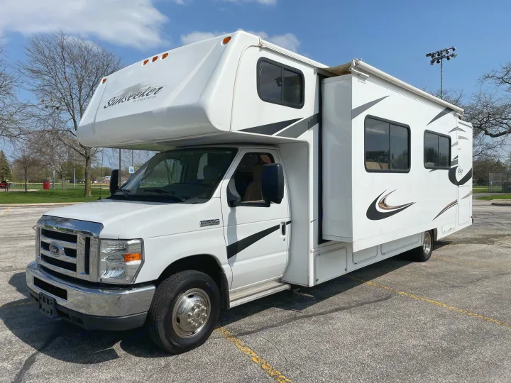 This spacious white Class C Sunseeker RV rental, built on a Ford chassis, is parked in a lot under a clear sky.. Forest River Sunseeker 2013