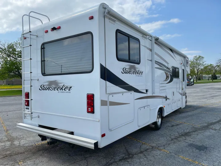 This white Sunseeker motorhome, ideal for your next rv rental, features a rear ladder, hitch, and side awning.. Forest River Sunseeker 2013