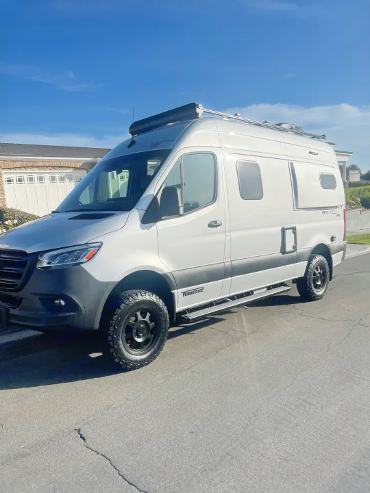Silver Winnebago Revel 4x4 camper van parked on a street, ideal for your next rv rental adventure.. Winnebago Revel 2022